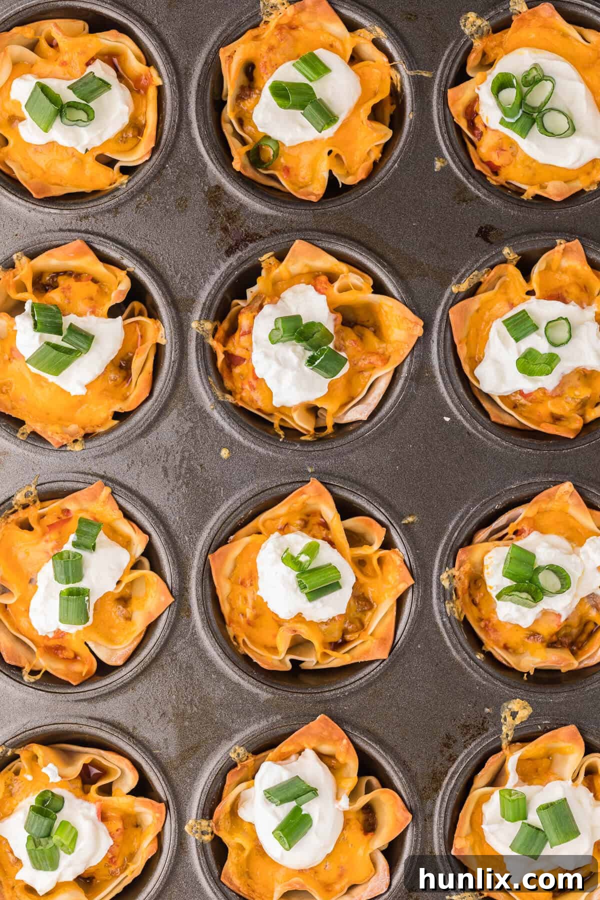 Crispy Taco Wonton Cups arranged beautifully in a muffin tin, filled with seasoned ground beef, melted cheese, and fresh toppings. The perfect easy appetizer for parties and family meals.