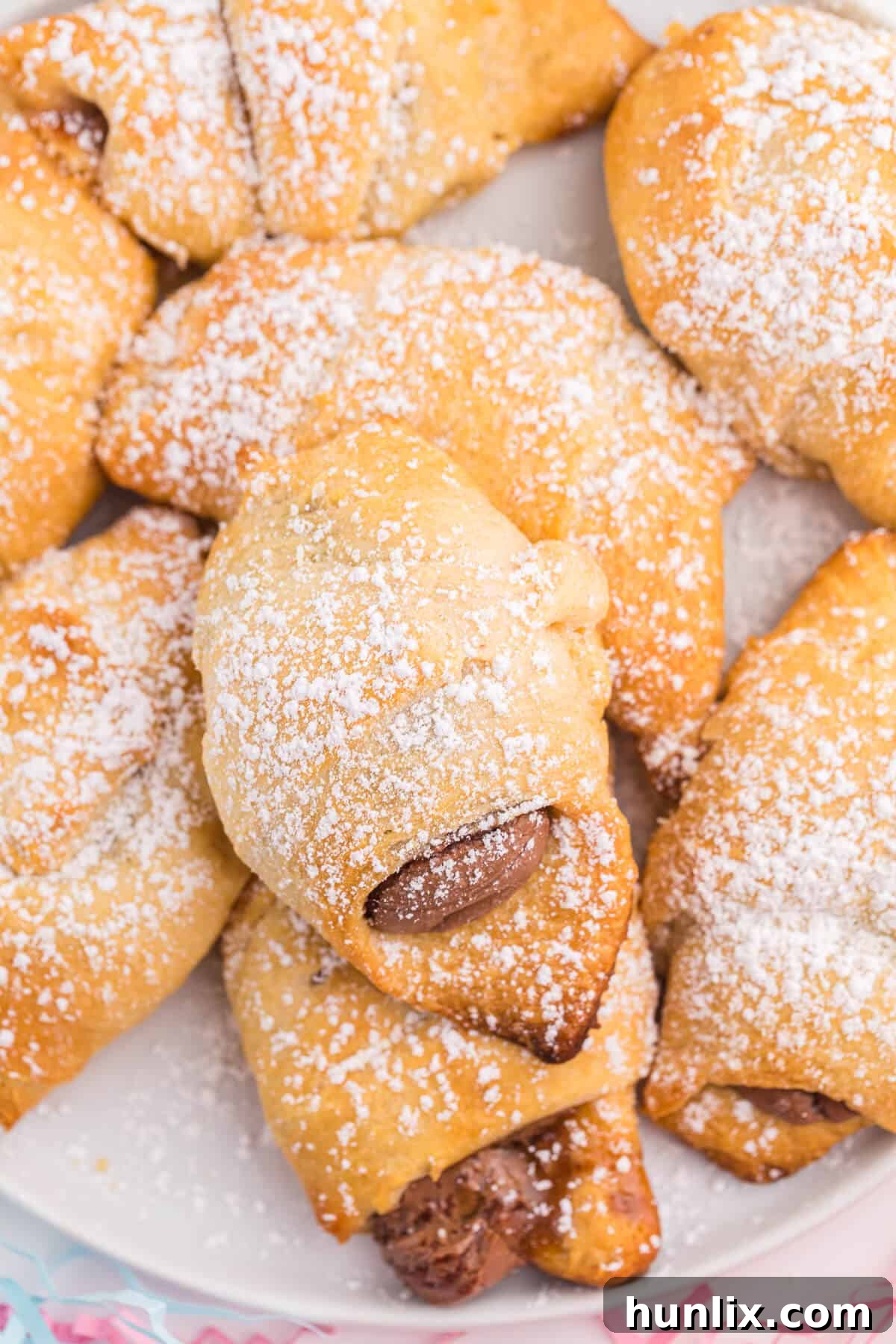 A close-up of crescent roll dough triangles with Cadbury Easter eggs placed at the wide end, ready for rolling.