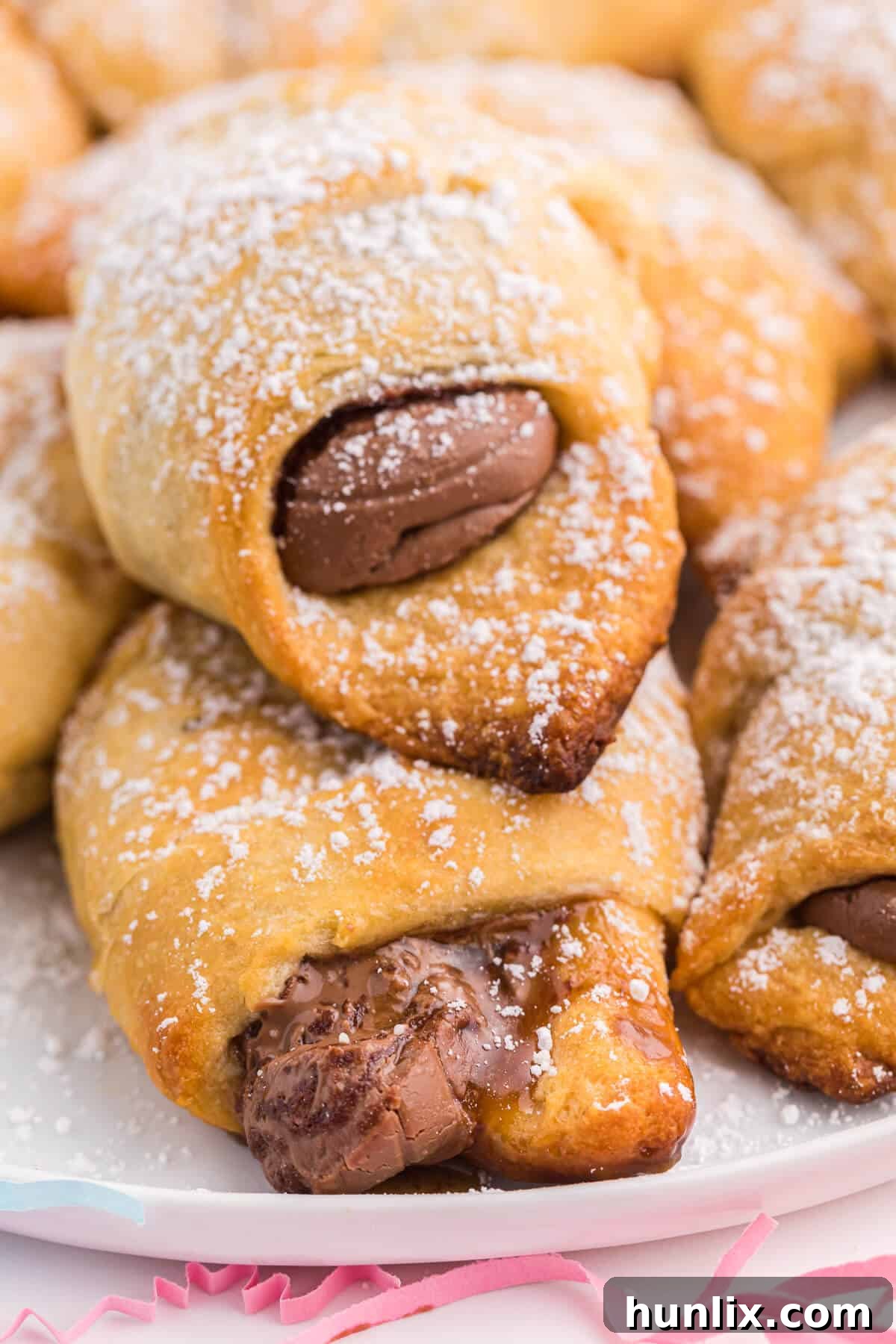 A single Easter egg stuffed crescent roll cut in half, revealing the perfectly melted chocolate center, resting on a white plate.