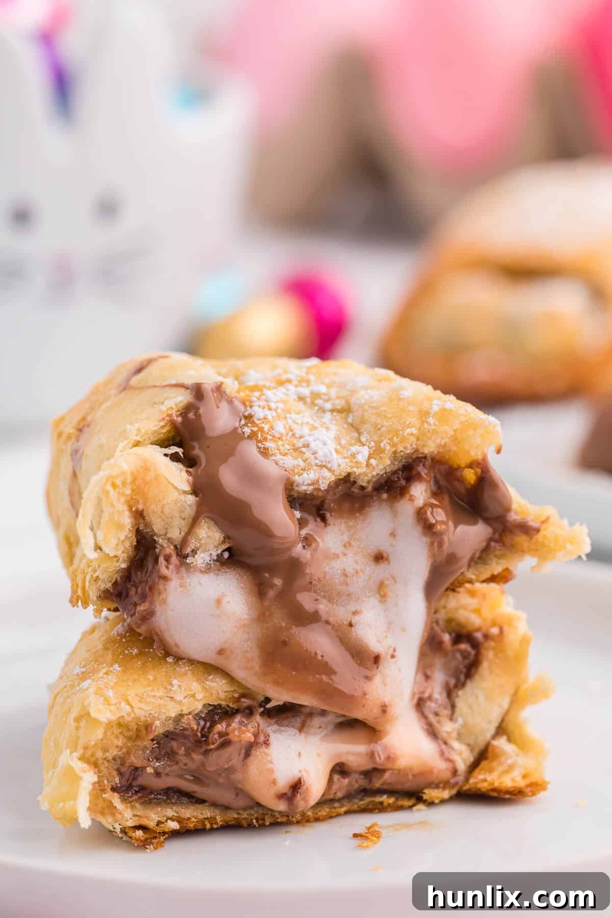 A freshly baked Easter egg stuffed crescent roll, sliced to reveal the gooey, melted chocolate center, on a white plate with a fork.