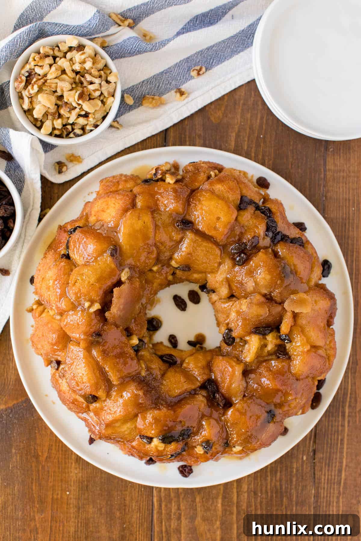 Caramel Cinnamon Monkey Bread 2 Classic monkey bread on a plate on a wooden table with ingredients and linens.
