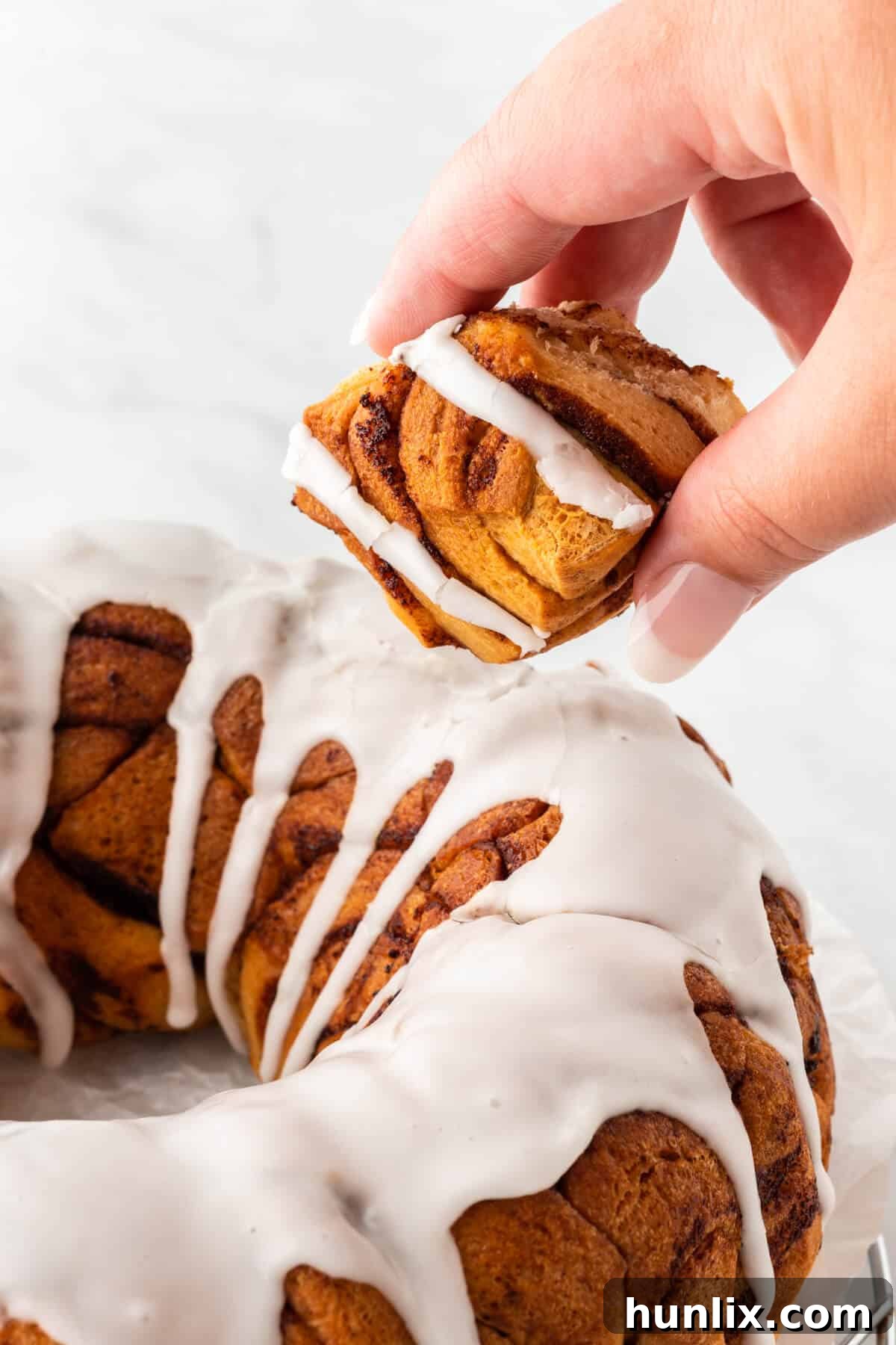 A hand holding a piece of cinnamon roll monkey bread.