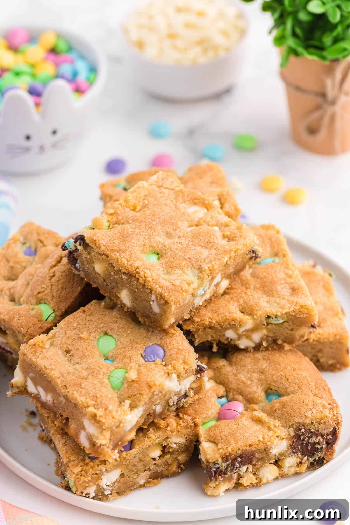 Spring Bloom Cookie Bars 4 A pristine white plate showcasing two neatly cut Spring Cookie Bars, rich with M&Ms and white chocolate, ready to be enjoyed.