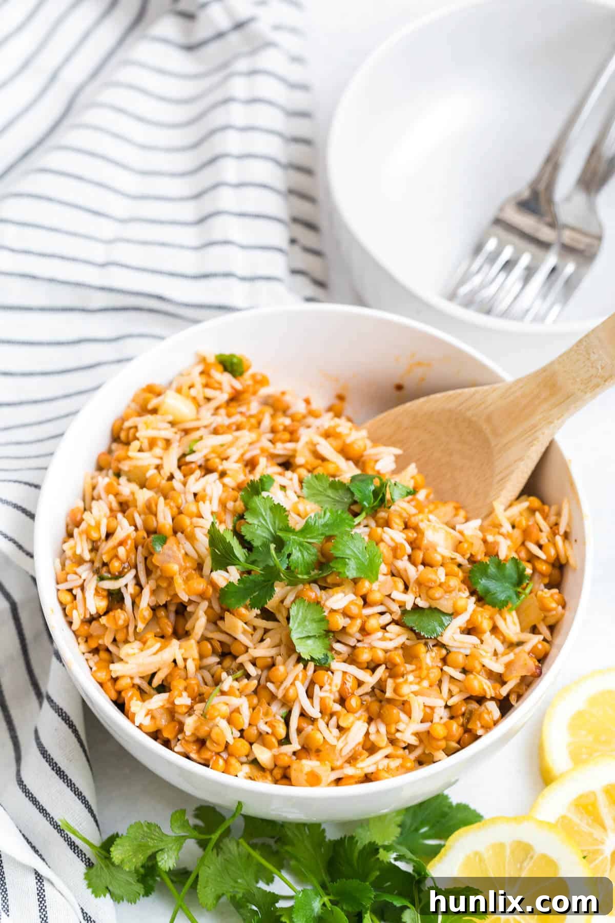 Golden Curried Lentil Rice 2 Curried lentil rice in a white bowl with a wooden serving spoon.