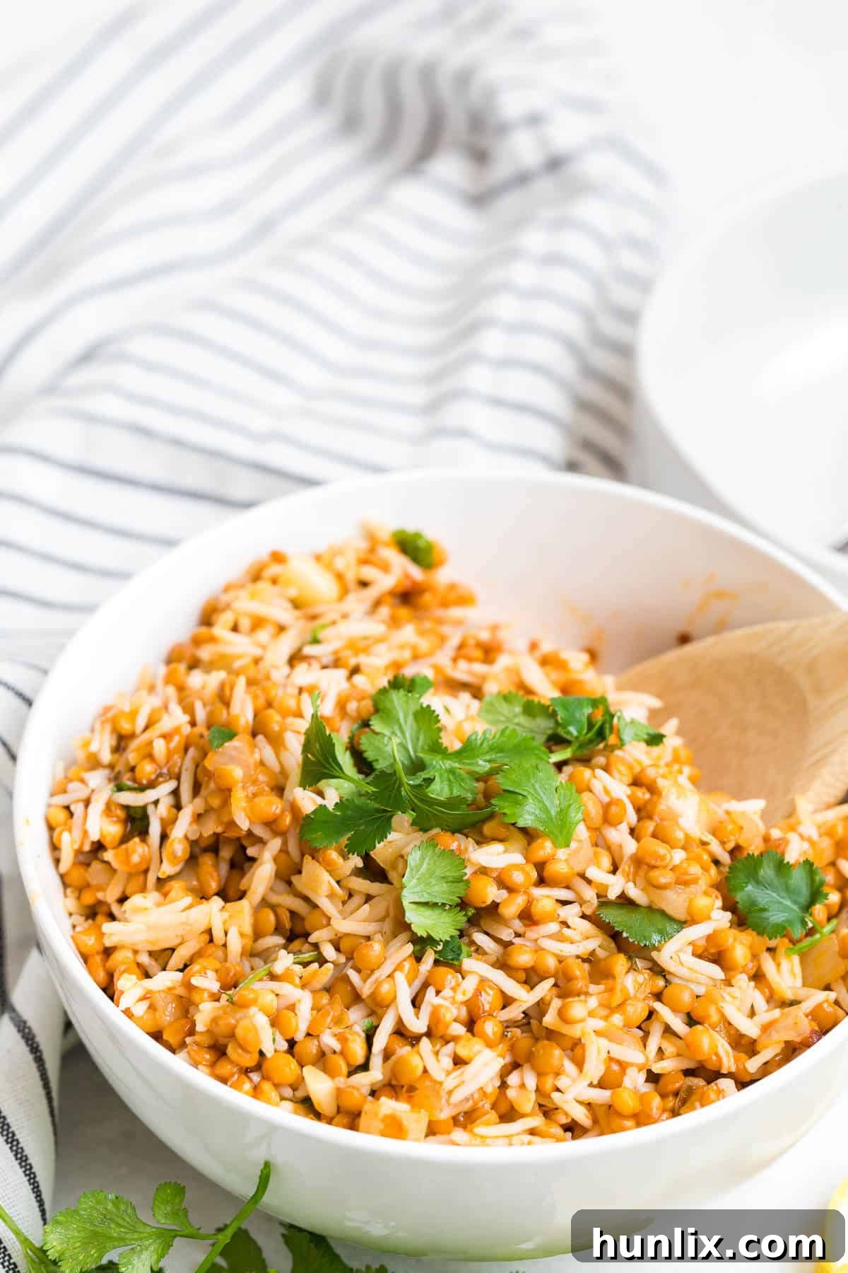Golden Curried Lentil Rice 3 Curried lentil rice in a bowl with a wooden spoon.