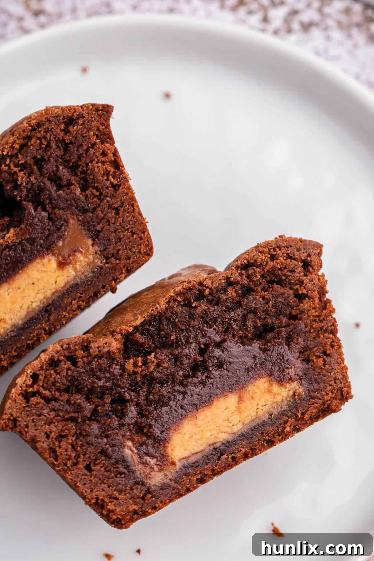 Reese's Peanut Butter Filled Brownies 5 A Reese's stuffed brownie cut in half on a plate, revealing the melted peanut butter cup center.