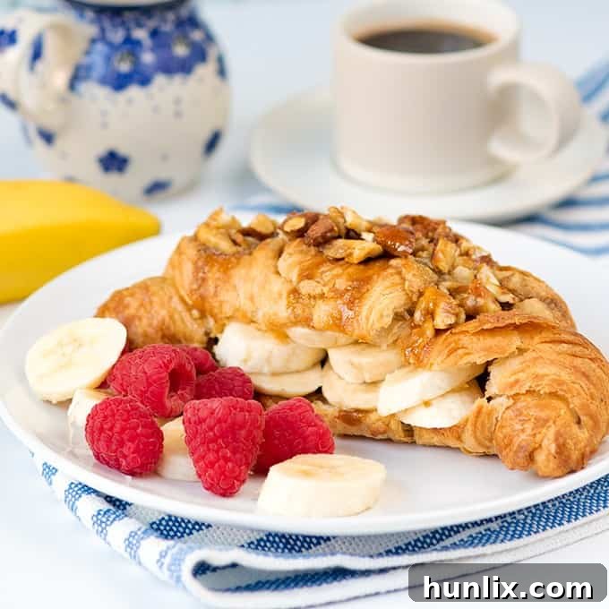 Sticky banana croissant on a plate with fresh fruit.