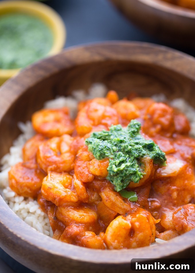 A close-up of a bowl of Tandoori Shrimp with Mint Chutney and rice, showcasing the texture and garnish.