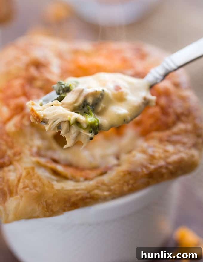 Comforting Chicken Broccoli and Cheddar Pot Pies 5 A close-up of the delicious filling of a Chicken, Broccoli & Cheddar Pot Pie, showcasing the melted cheddar cheese, tender chicken, and vibrant broccoli florets.