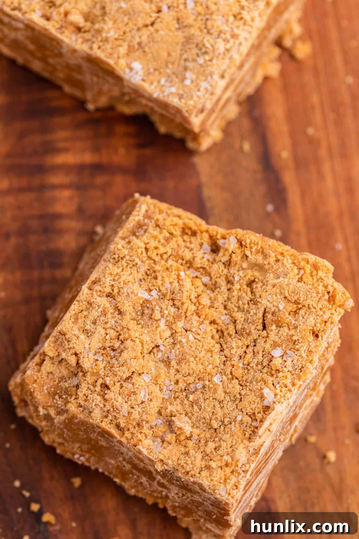 Salted Caramel Delight Fudge 6 Salted caramel fudge square on a wooden cutting board.