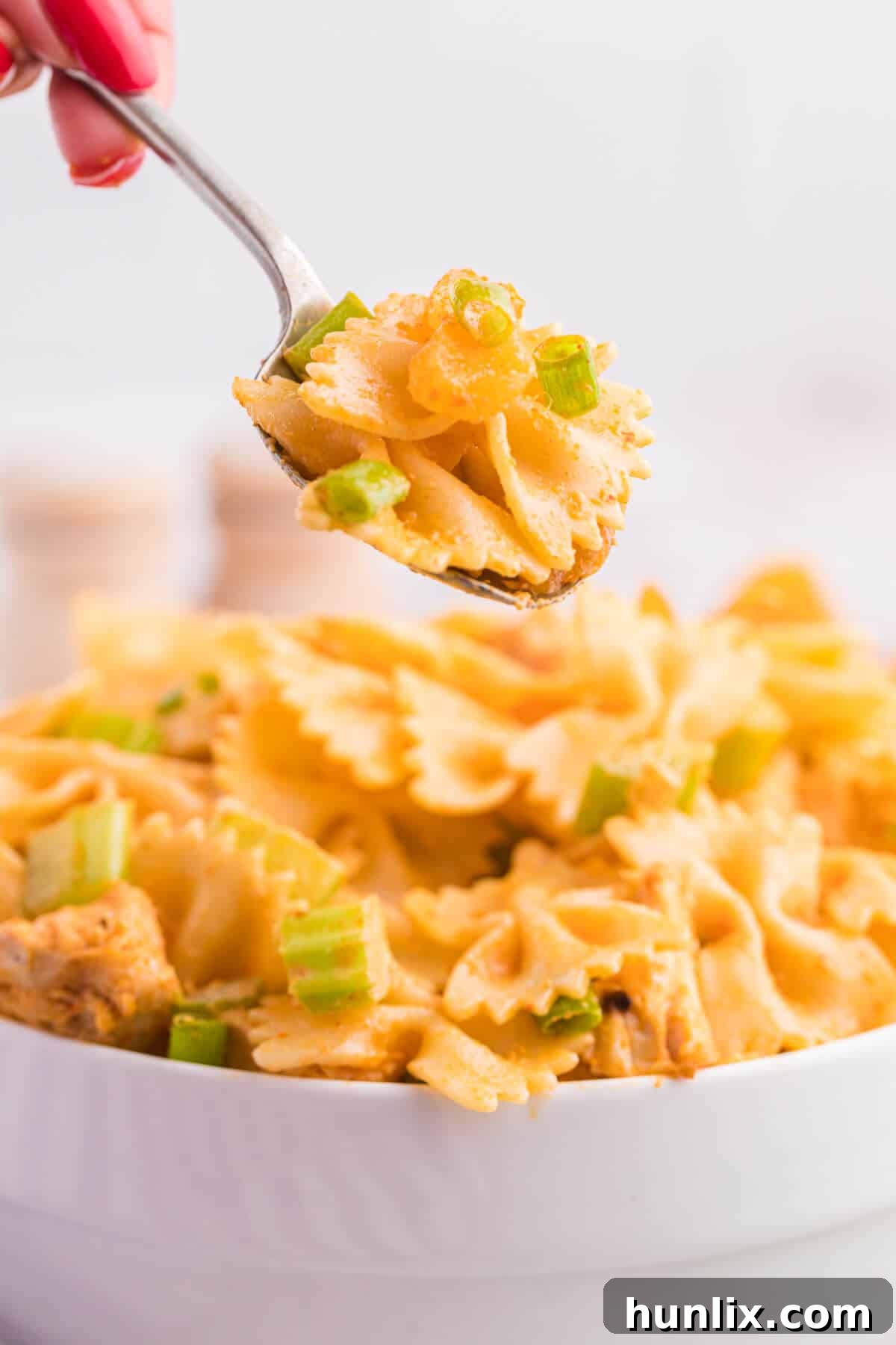 Golden Curry Chicken Pasta Salad 6 A spoon scooping creamy curried chicken pasta salad from a bowl.