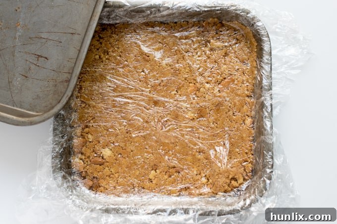A perfectly pressed graham cracker crust chilling in a square pan.