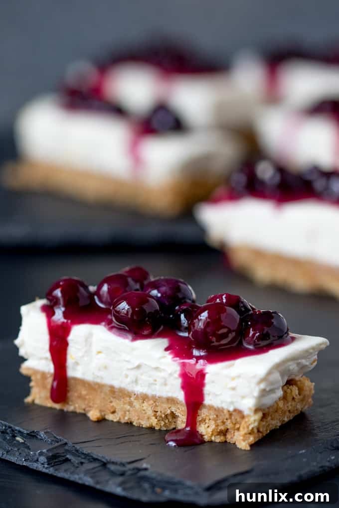 A stunning arrangement of blueberry and lemon cheesecake bars on a dark surface, ready to serve.