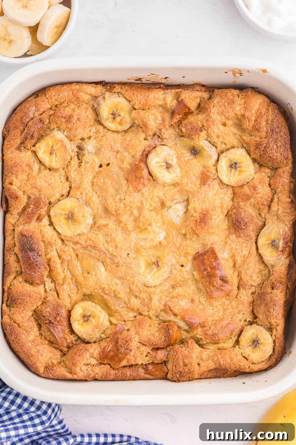 Golden-brown Banana Bread Breakfast Casserole in a white baking dish, ready to be served.