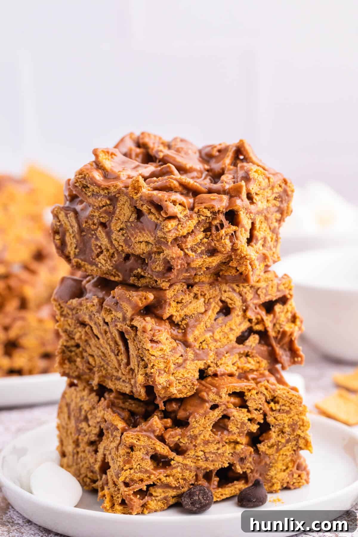 A stack of 3 individual indoor s'mores bars presented on a small ceramic plate.