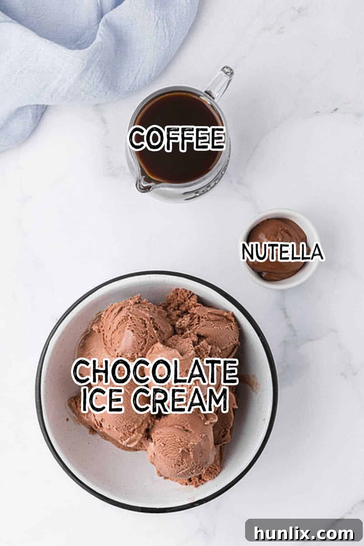 Various ingredients for a Nutella coffee milkshake neatly arranged on a marble countertop.