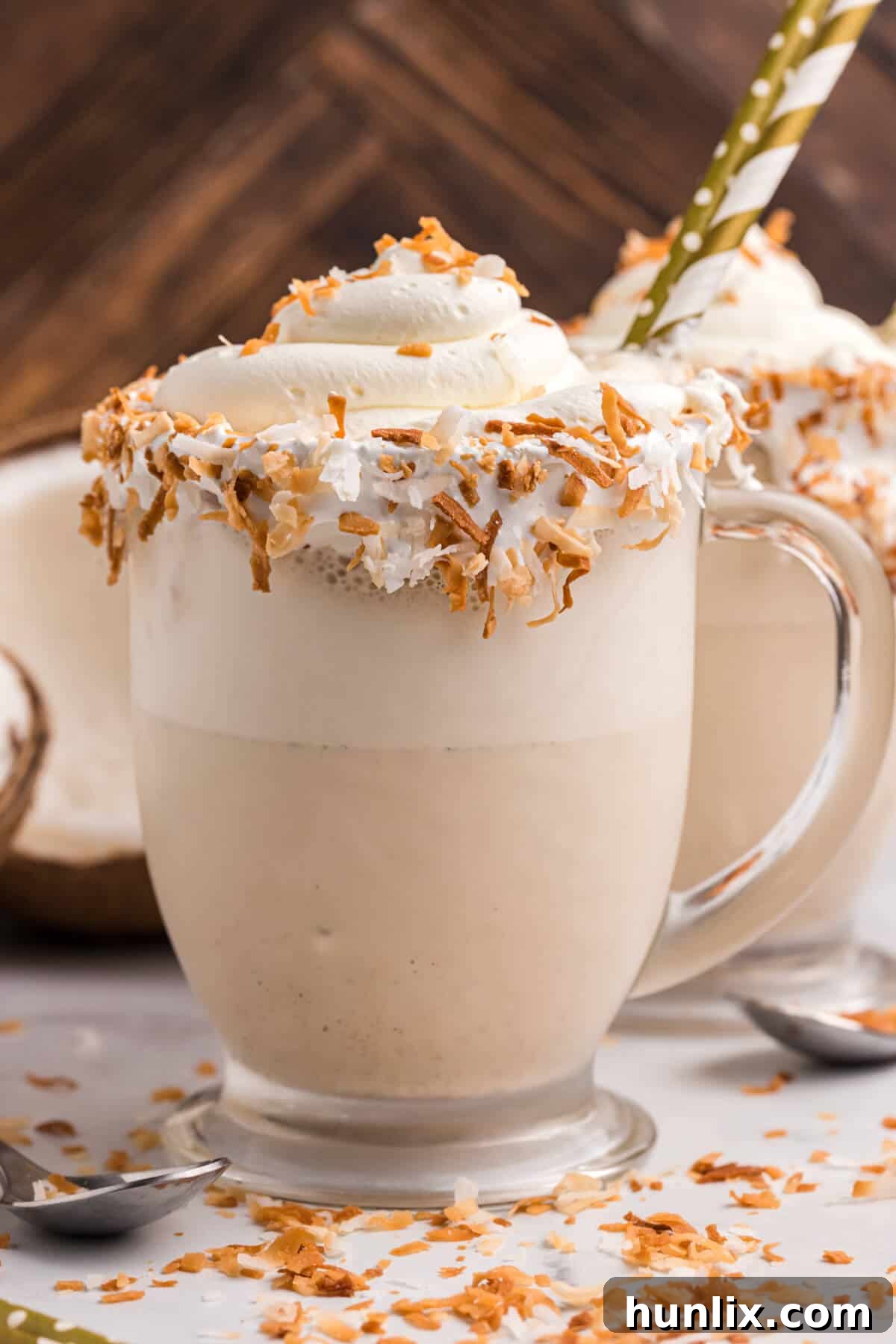 A close-up of the Coconut Coffee Milkshake in a glass with a straw, showing the whipped cream and toasted coconut topping.