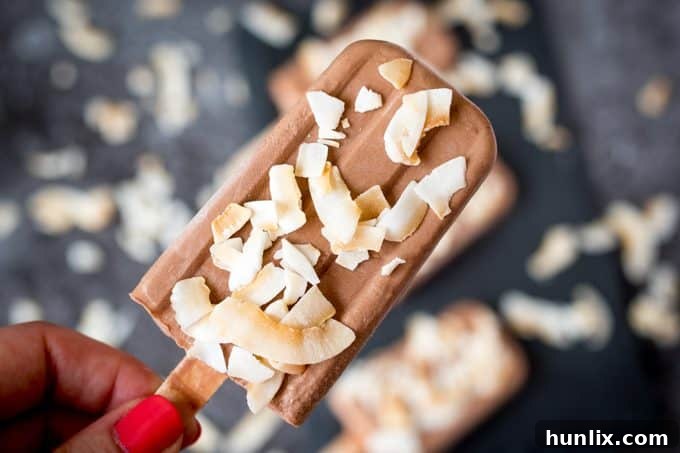 A hand holding a toasted coconut fudgsicle.