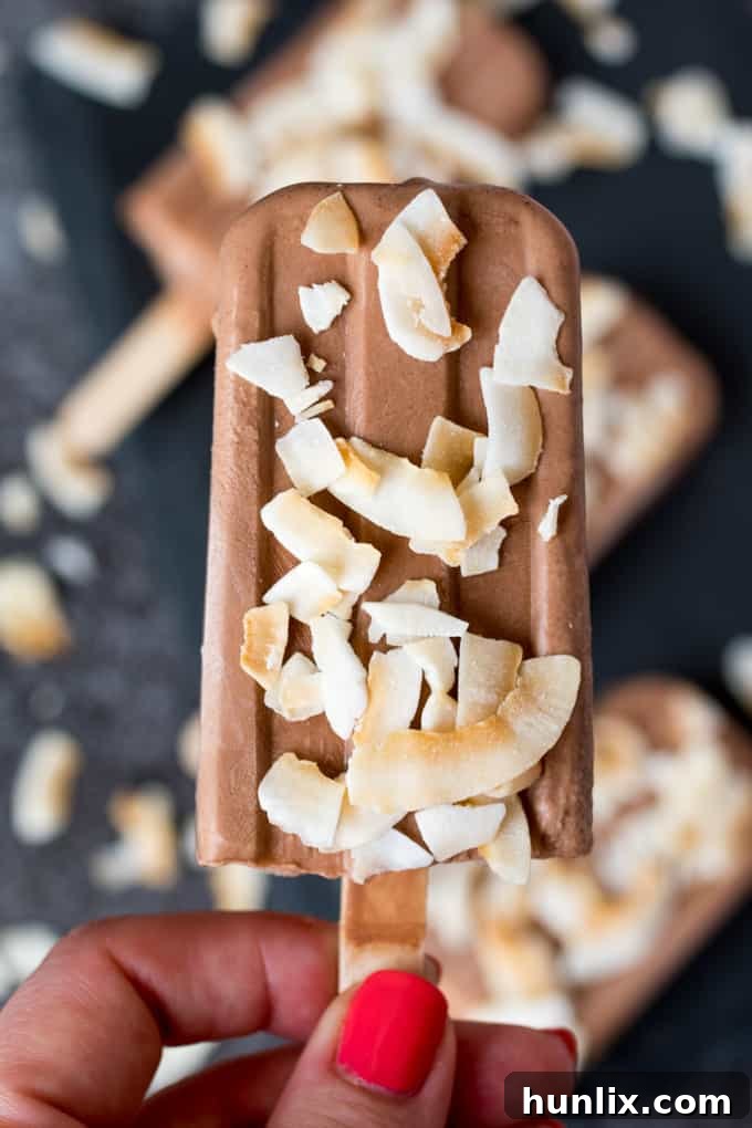A hand holding a toasted coconut fudgsicle.