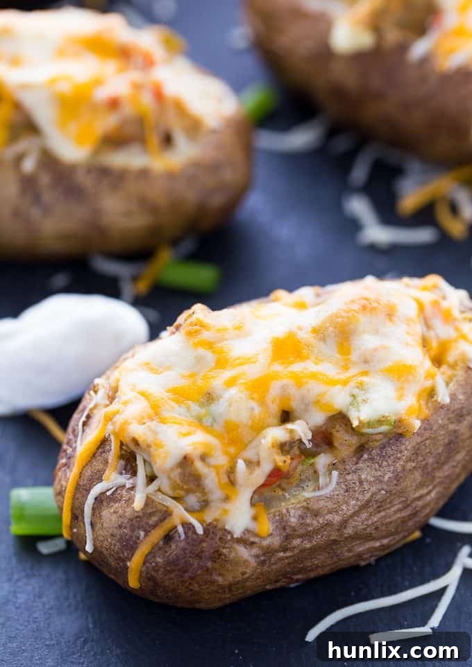 Interior of a baked potato being carefully scooped out to create a perfect shell for stuffing in Twice Baked Pepper Stuffed Potatoes.
