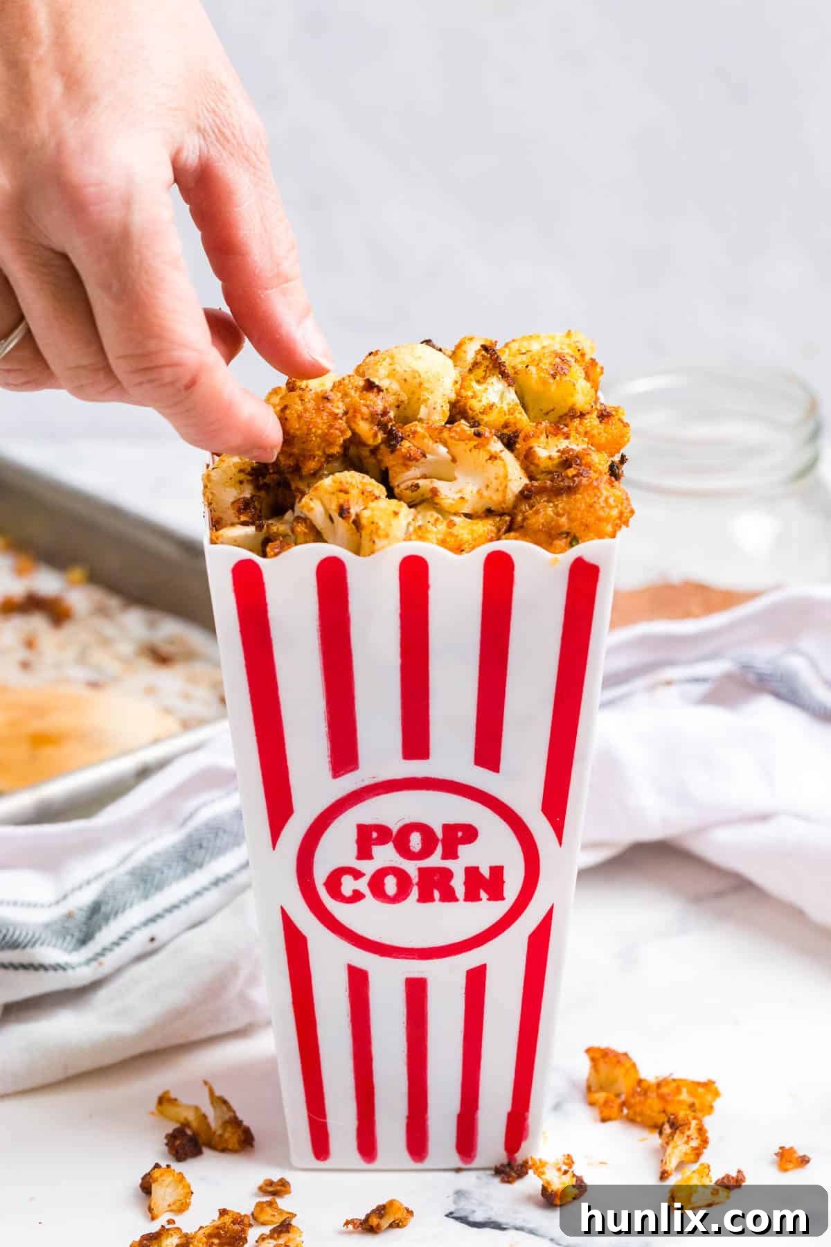 Spicy Buffalo Popcorn 7 A hand reaching into a container filled with crispy Buffalo Cauliflower Popcorn, emphasizing its irresistible nature.