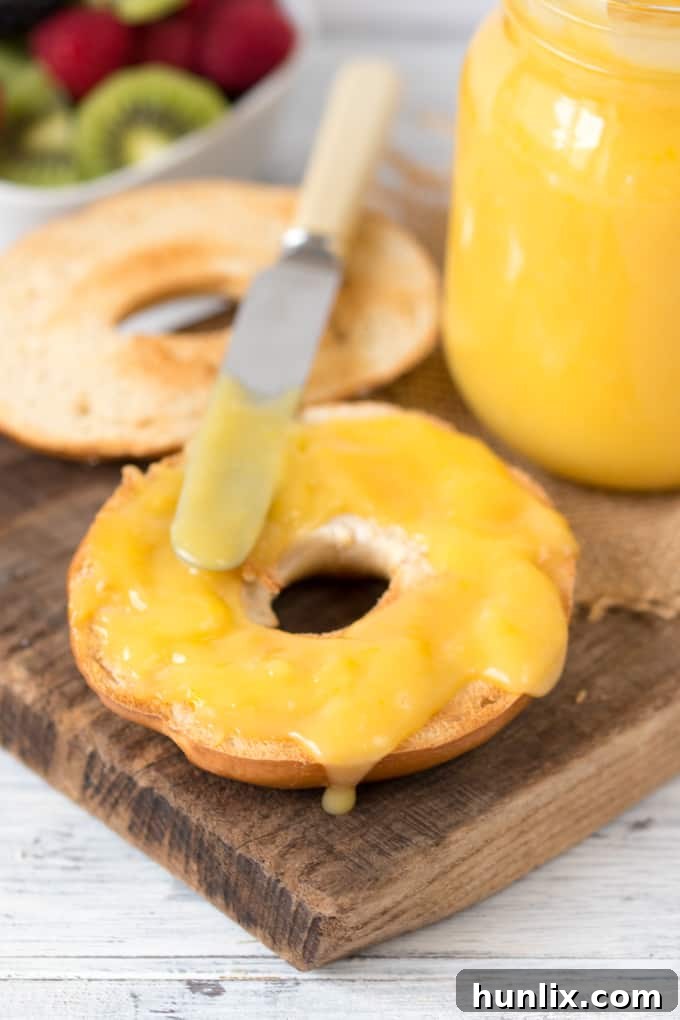 Homemade lemon curd on a bagel with a butter knife.