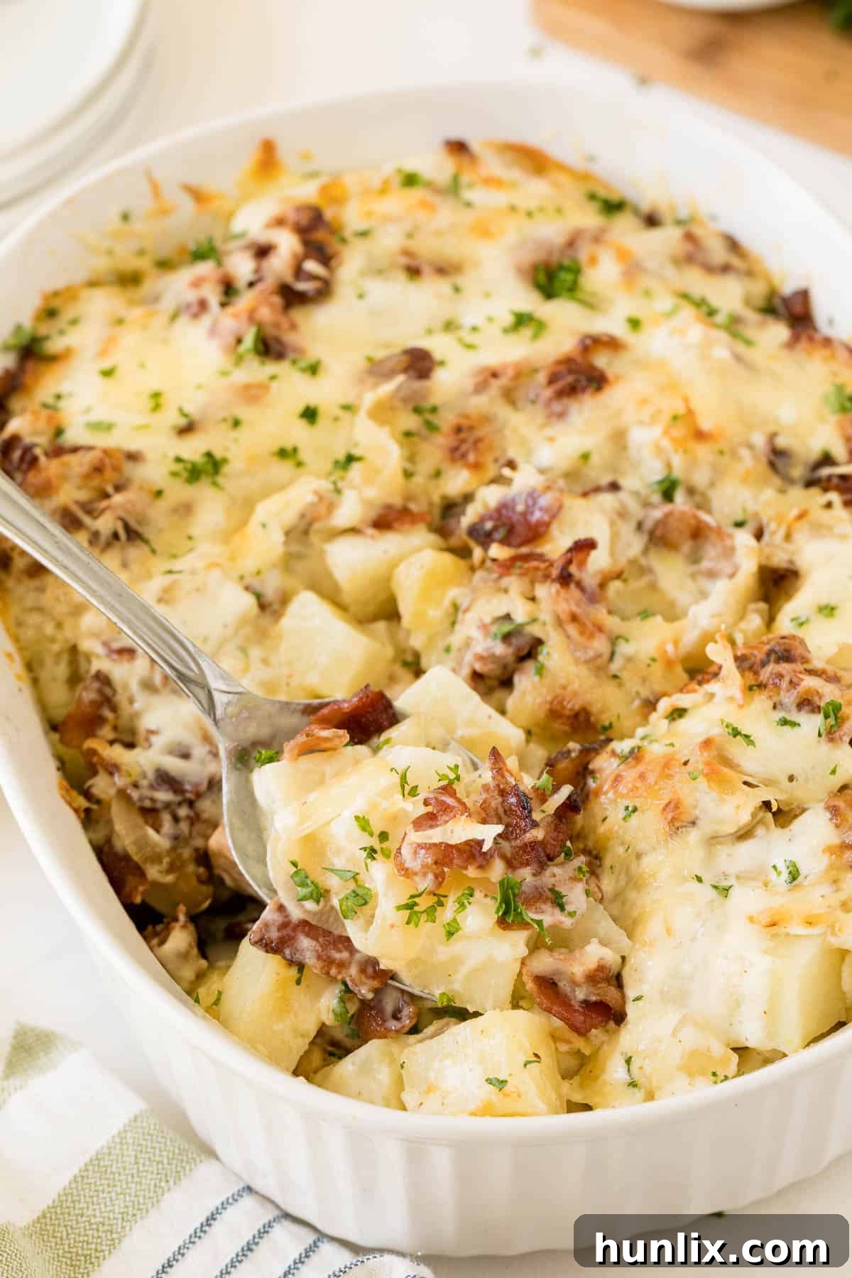 Crispy Bacon Ranch Potatoes 5 A close-up shot of Bacon Ranch Potatoes in a casserole dish with a serving spoon, highlighting the layers and texture.