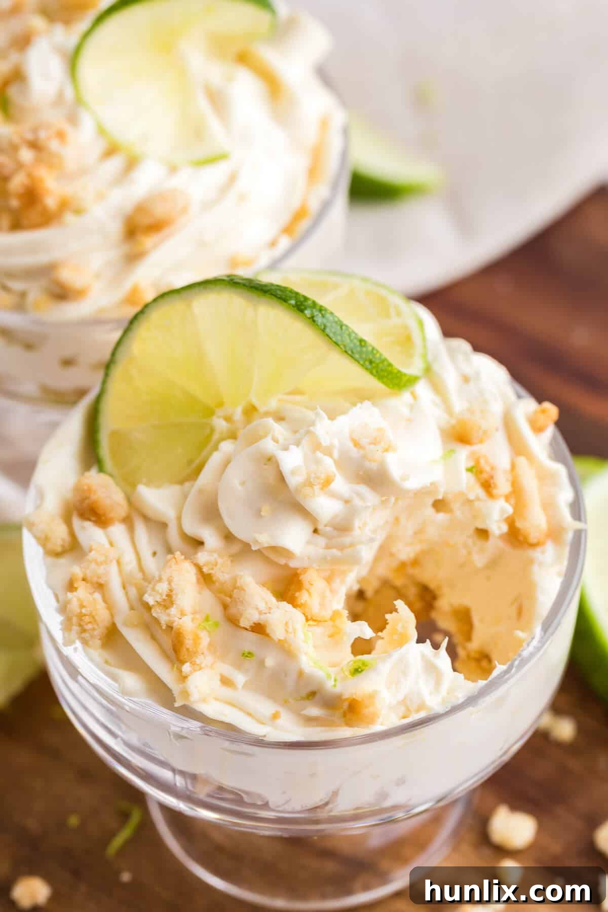 A close-up shot of a single lime cheesecake parfait, highlighting its creamy layers and crumbly topping.