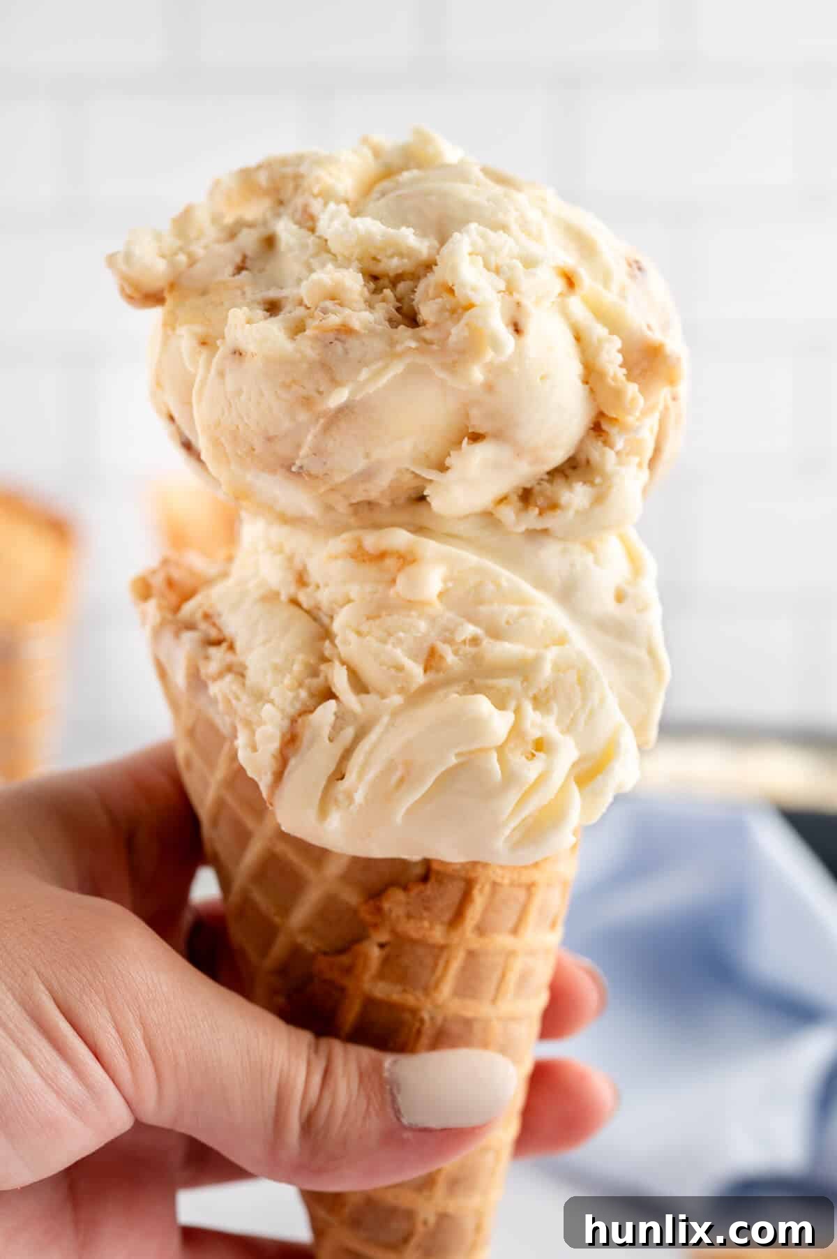 A hand holding a toasted marshmallow ice cream cone with a blurred background.