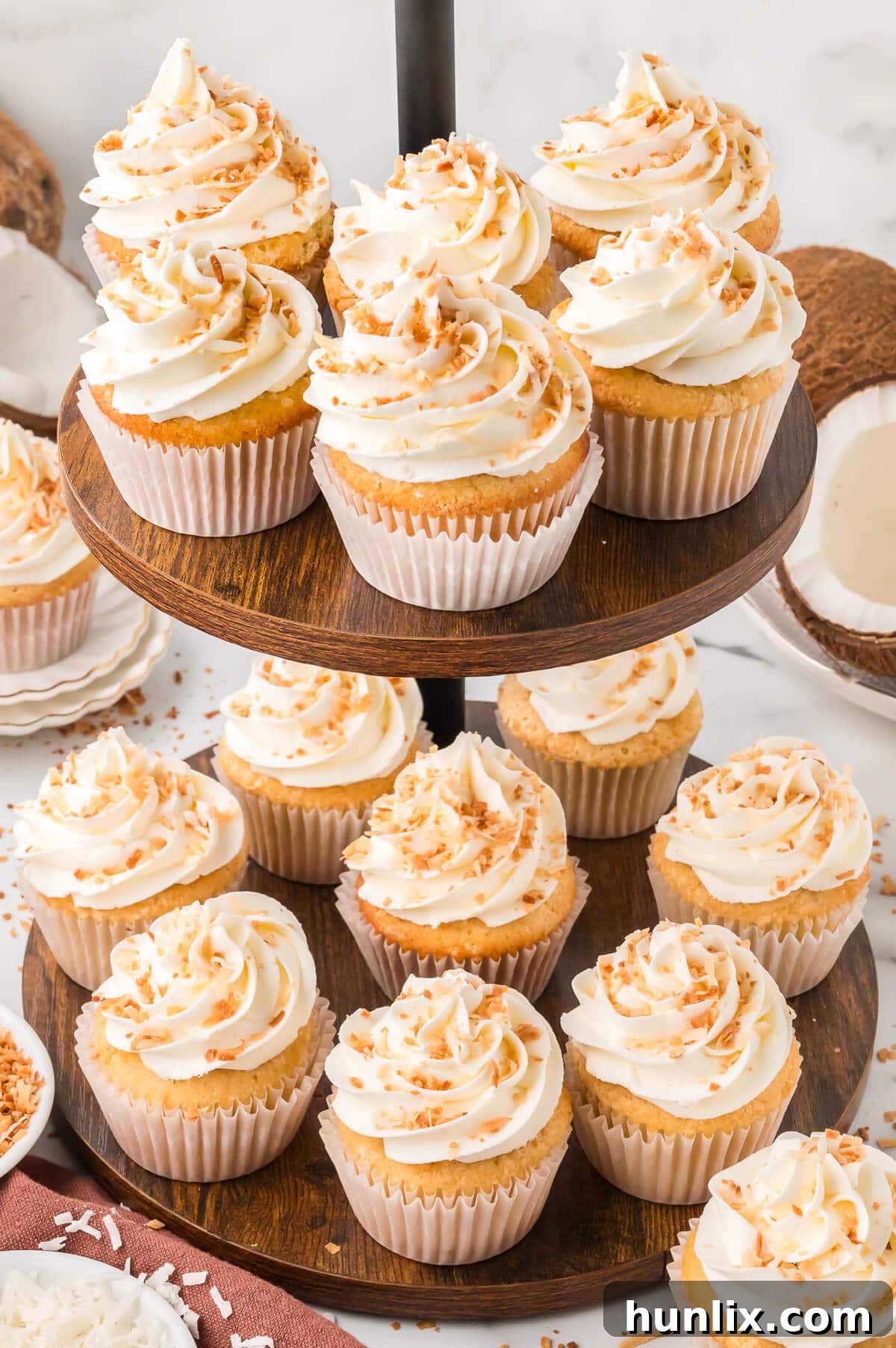 Beautifully frosted coconut cream pie cupcakes arranged on an elegant white cupcake stand, ready to be served.