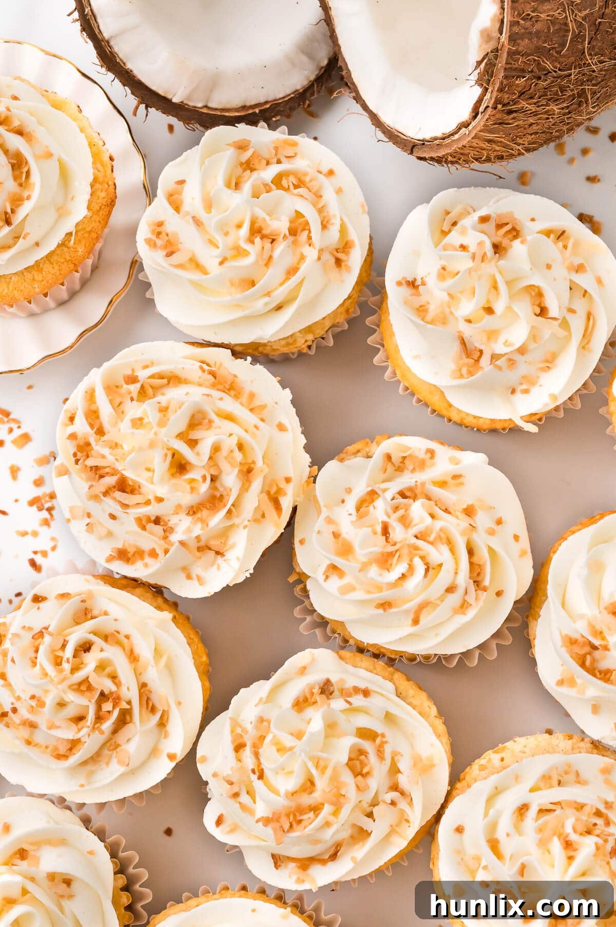 A close-up shot of freshly baked and frosted coconut cream pie cupcakes on a clean white surface, showcasing their delicious appeal.