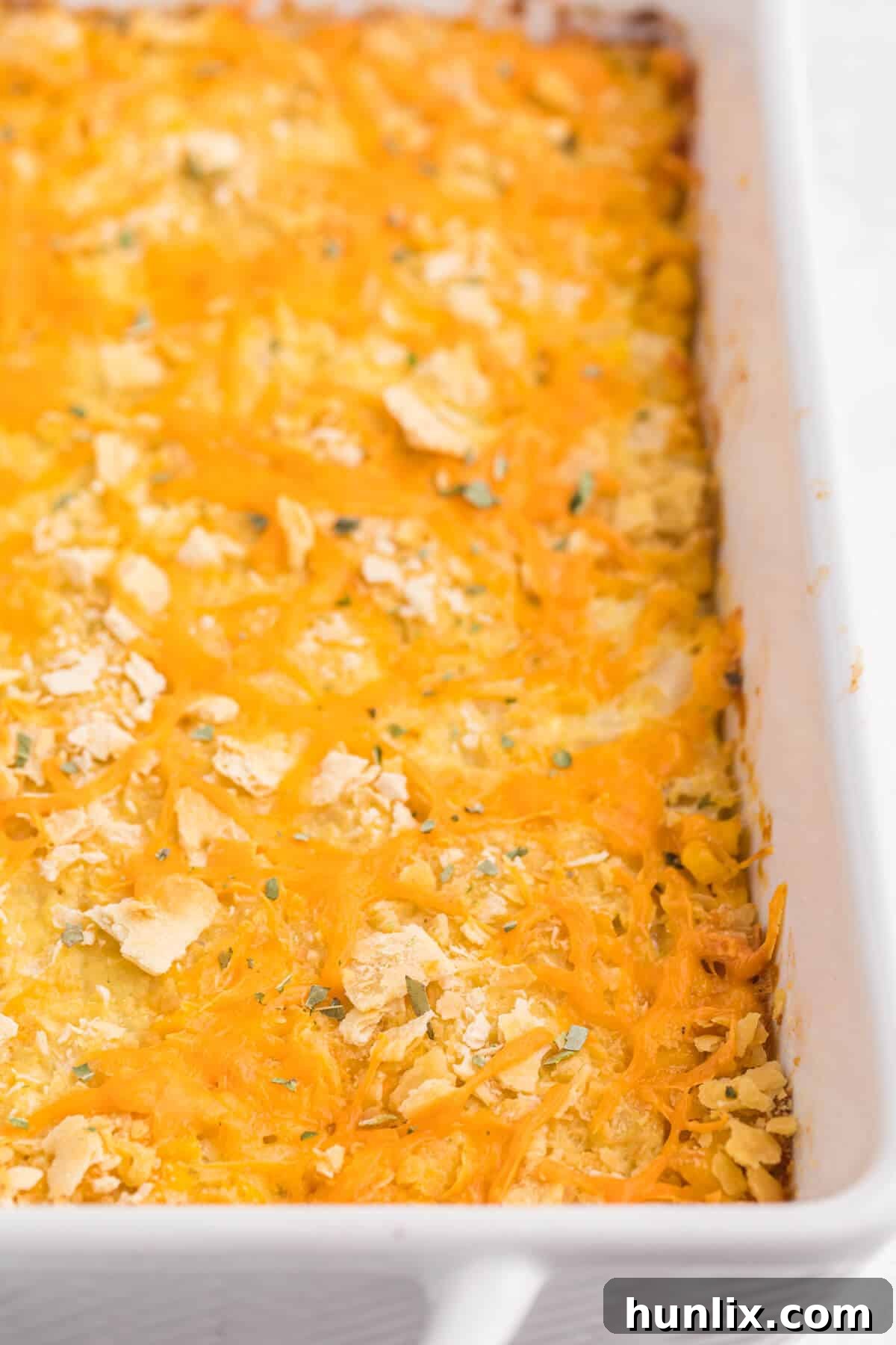 Cheesy corn casserole in a pan, ready to be served.