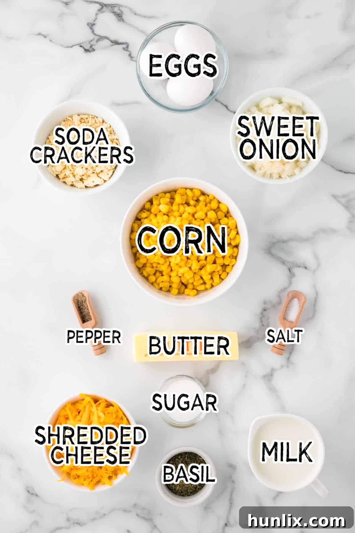 Ingredients for cheesy corn casserole laid out on a marble counter.