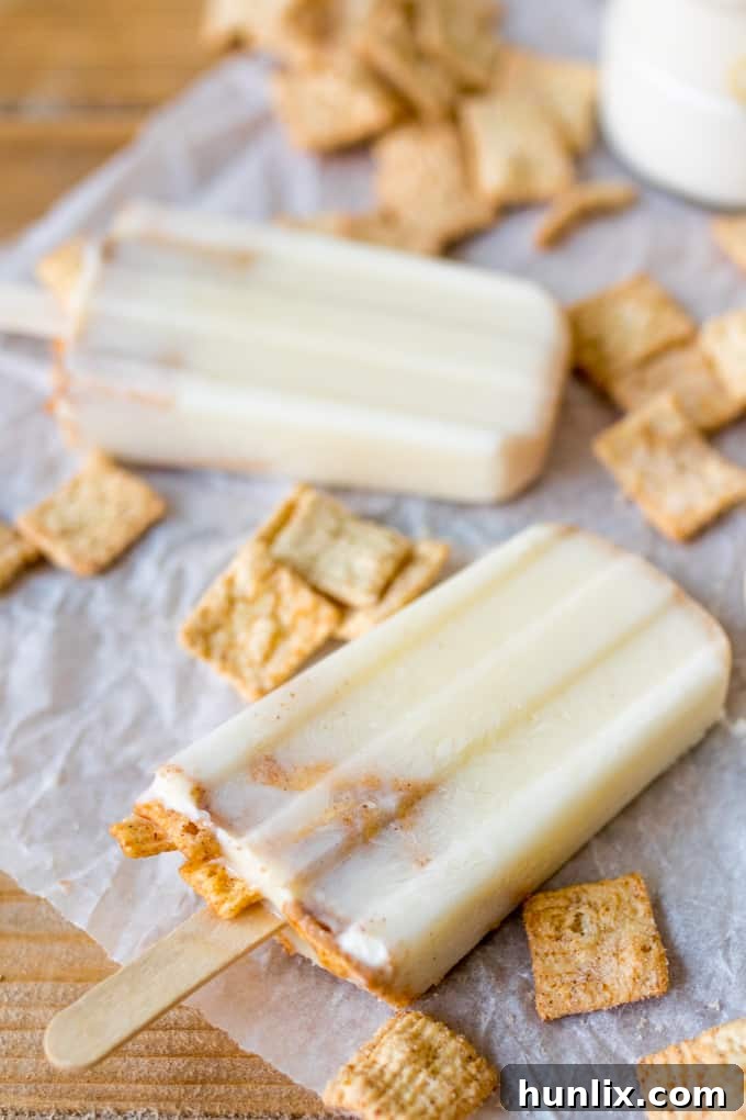A close-up shot of several cereal milk popsicles laid flat on parchment paper, showing their smooth, creamy texture.