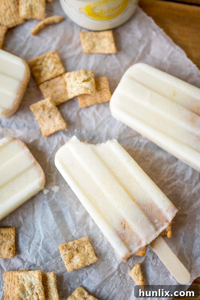 A delicious cereal milk popsicle with a bite taken out, showing its creamy interior and small cereal pieces.