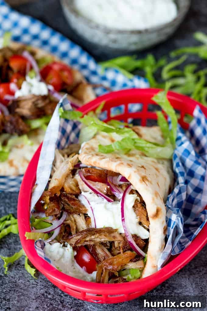 A beautifully presented serving of pork gyros with pita, fresh salad, and homemade sauces, ready to be devoured.