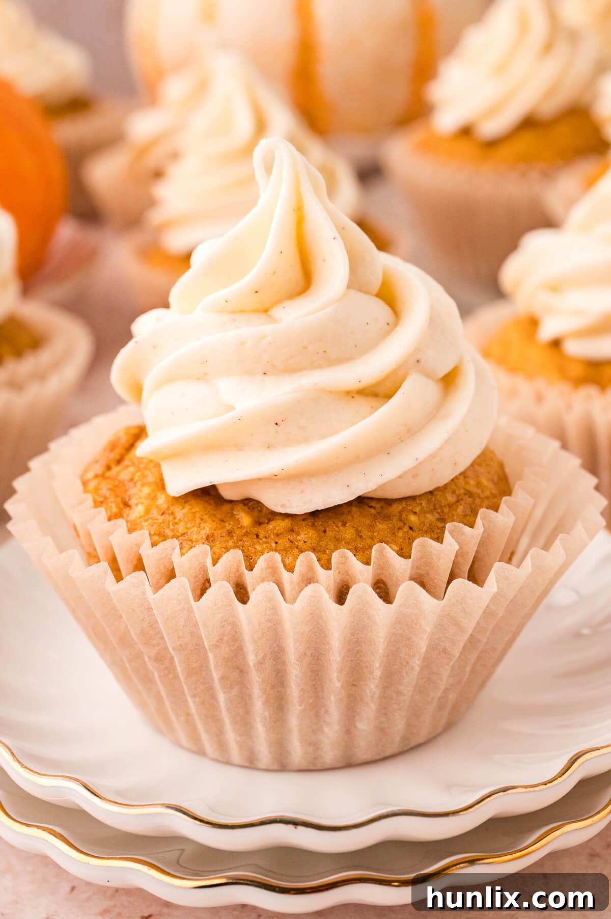 A single, beautifully frosted Pumpkin Pie Cupcake presented on a pristine white plate, inviting a delicious bite.