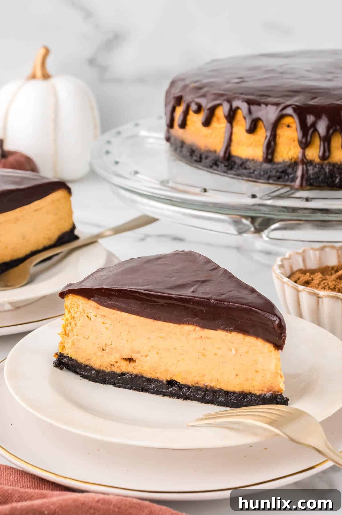 A slice of chocolate pumpkin cheesecake on a plate, showing its perfectly set layers and ganache.