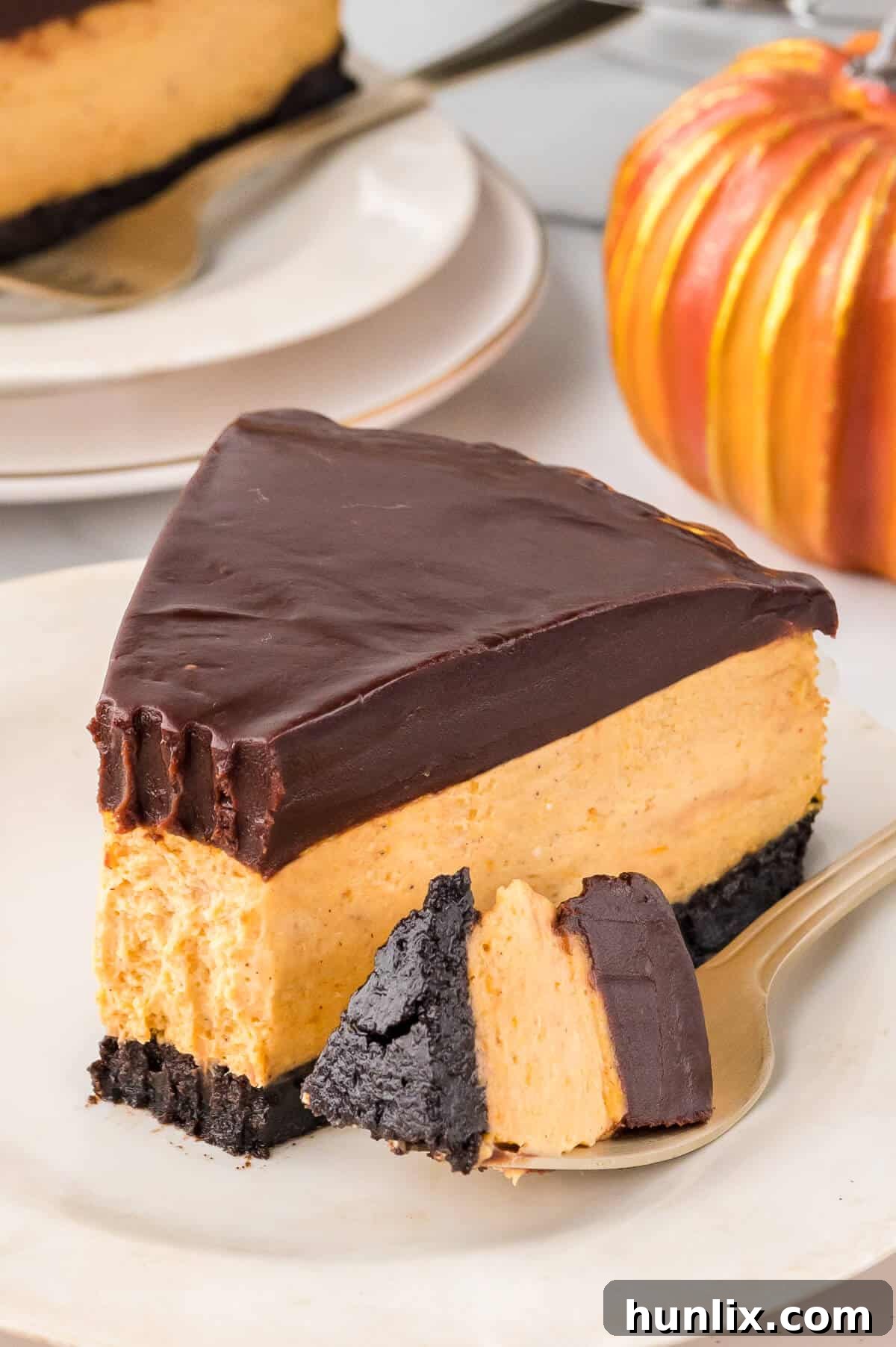 A partially eaten slice of chocolate pumpkin cheesecake, with a fork holding a small bite.