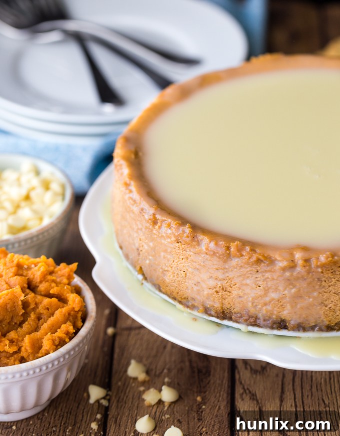 A stunning slice of white chocolate pumpkin cheesecake, featuring a golden-brown crust, creamy orange filling, and a luscious white chocolate glaze, garnished for a festive fall dessert.