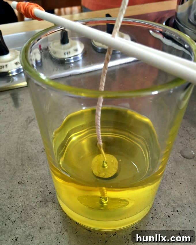 Crafting Layered Jar Candles 7 First layer of yellow soy wax poured into a candle jar, with wick centered.