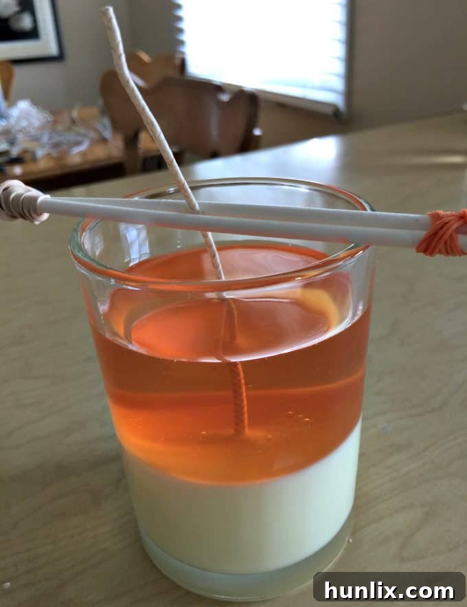 Crafting Layered Jar Candles 8 Second layer of coral-colored wax being poured onto the hardened yellow layer.