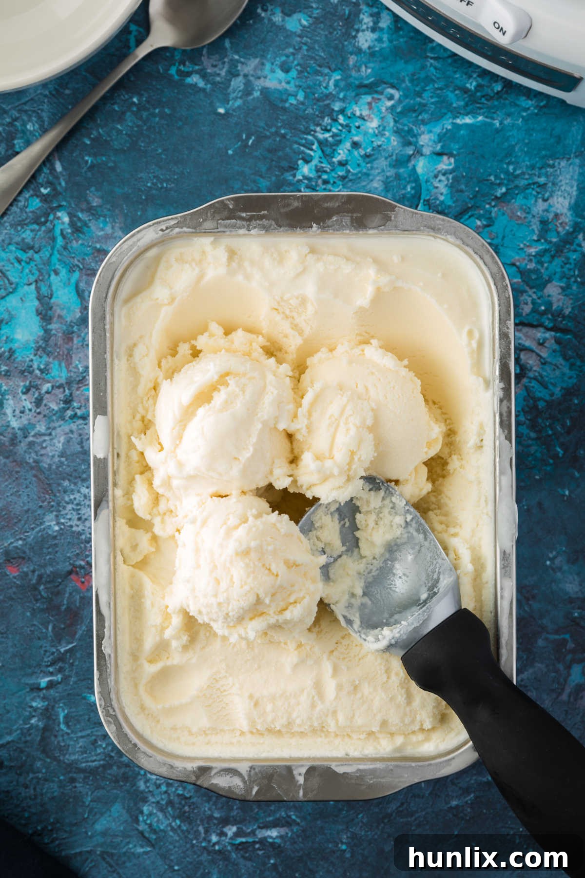 A tub of homemade vanilla ice cream with an ice cream scoop, perfectly frozen and ready to enjoy.