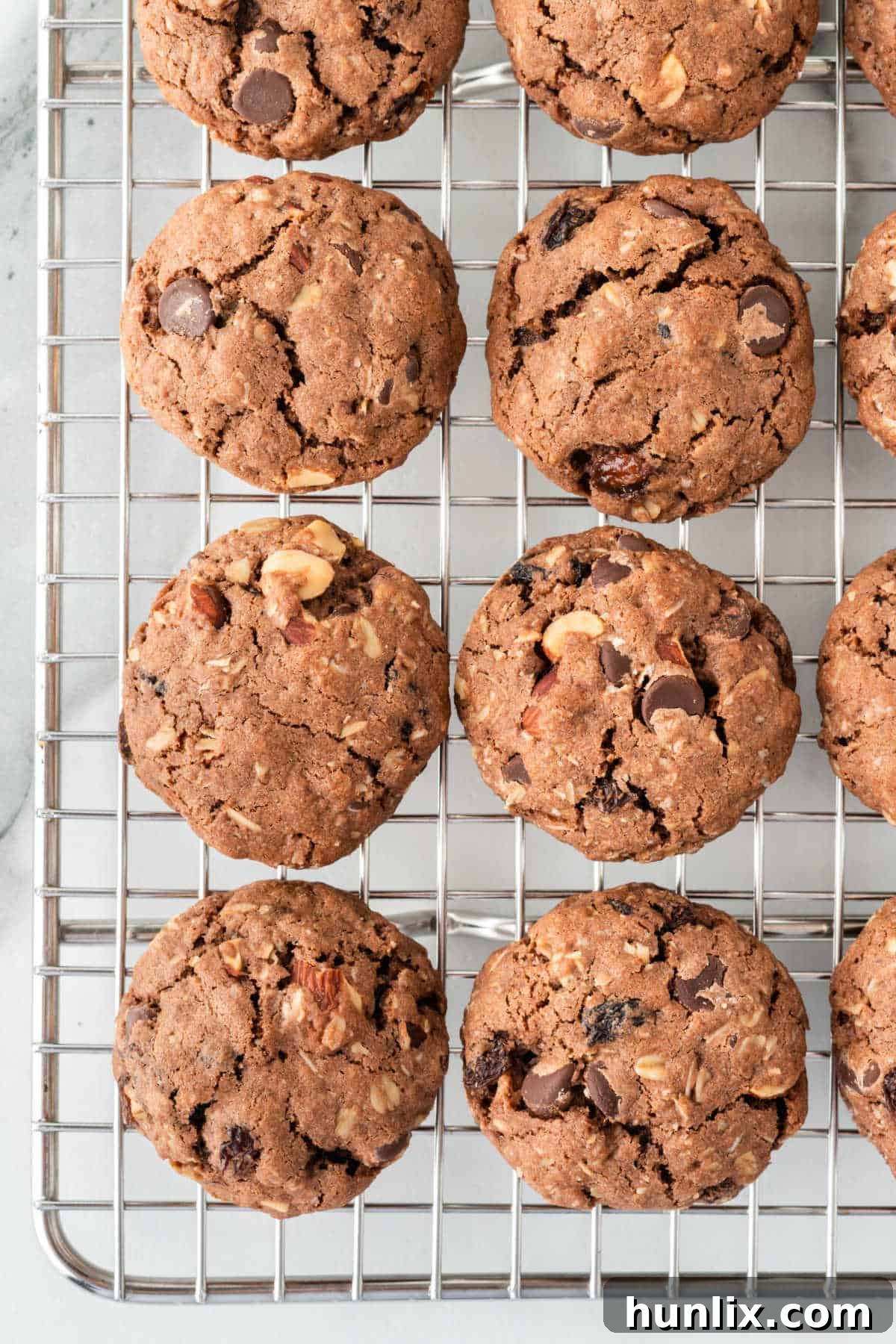 A wire rack filled with freshly baked, golden brown Cowboy Cookies, showcasing their rich texture and mix-ins like chocolate chips, oats, and nuts.