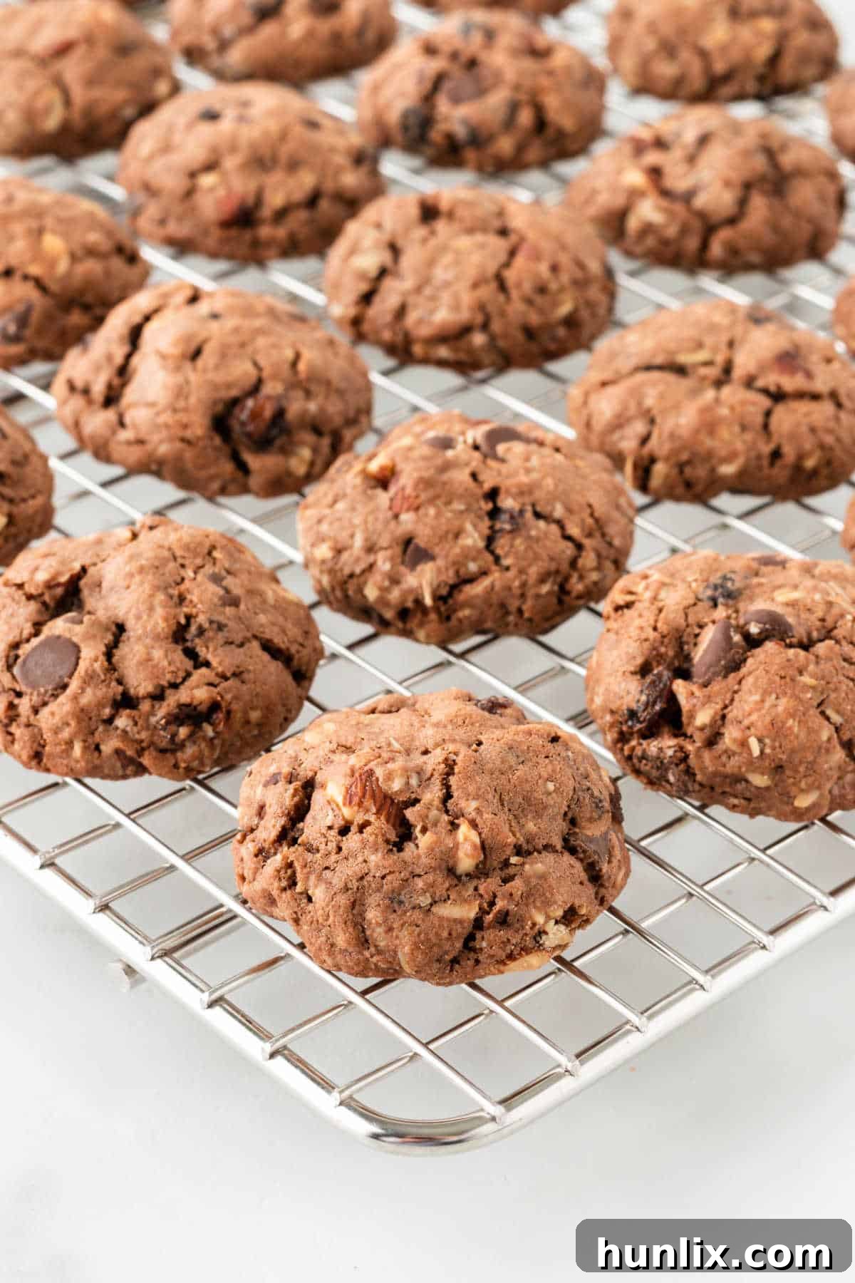 A close-up of freshly baked Cowboy Cookies cooling on a wire rack, with their inviting golden-brown edges and visible mix-ins.