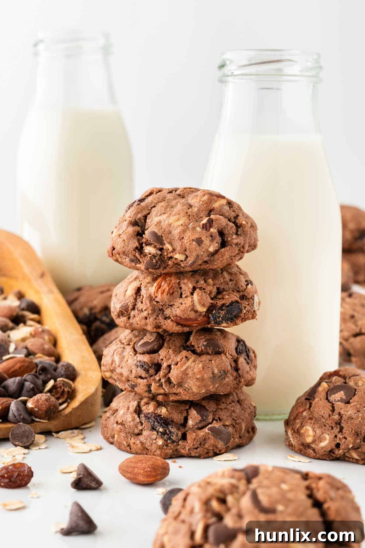 A charming stack of Cowboy Cookies next to a jug of milk, invitingly presented on a wooden surface, suggesting a perfect snack pairing.