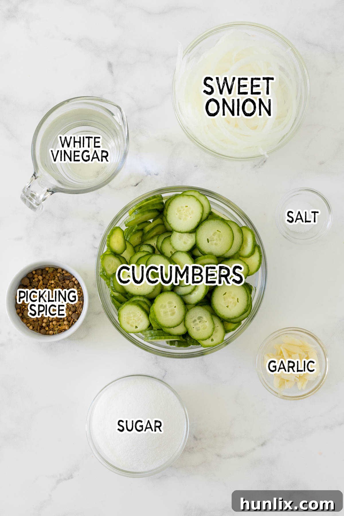 Fresh ingredients laid out for making refrigerator pickles, including thinly sliced cucumbers, onions, and various pickling spices.