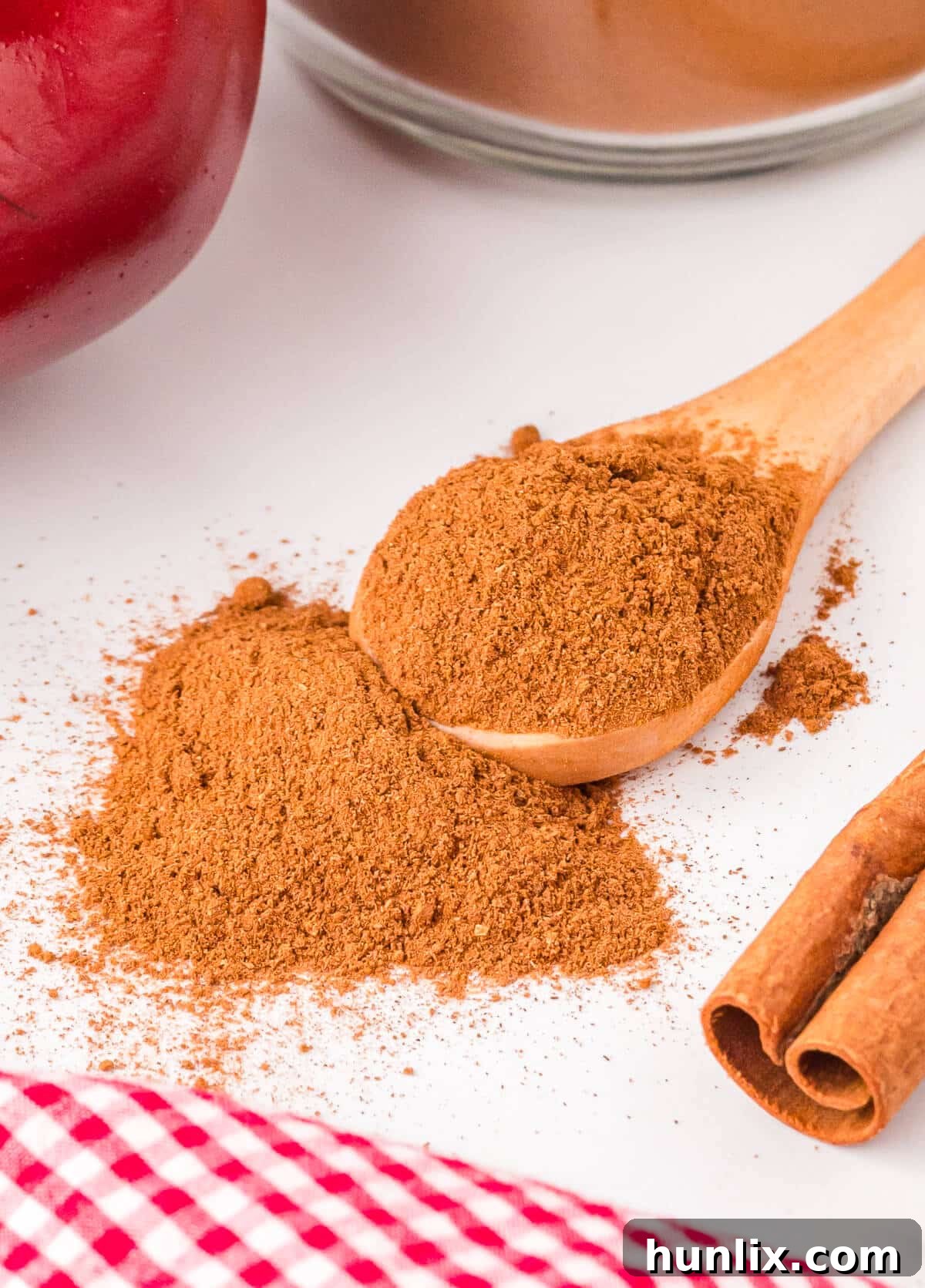 A small mound of finely ground apple pie spice rests on a piece of parchment paper, showcasing its rich brown color and fine texture, ready for use in fall baking.