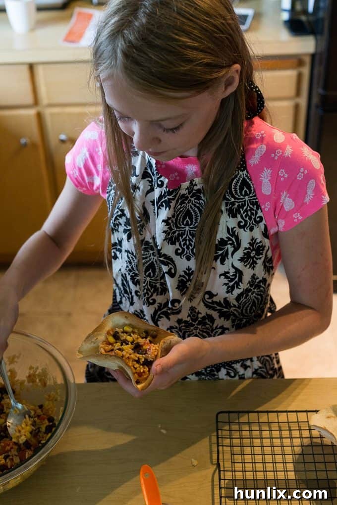 Children carefully filling their baked taco bowls with the black bean and rice mixture.