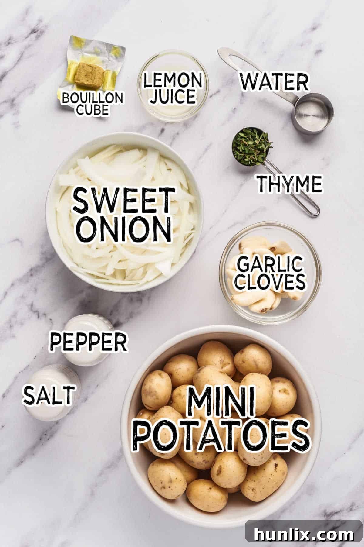 Garlic-Infused Slow Cooker Potatoes 3 Fresh ingredients laid out for making slow cooker garlic potatoes: mini potatoes, garlic, sweet onion, lemon, water, bouillon cube, and thyme.